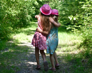 Twee meisjes lopen samen door een bos.